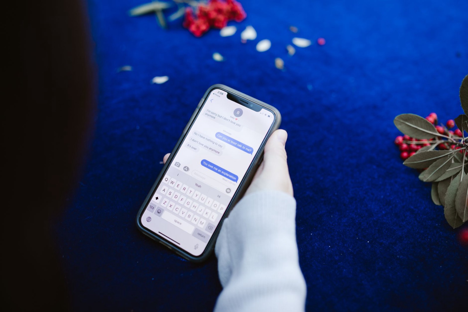 Deux mains tiennent un smartphone ouvert sur une conversation de messagerie